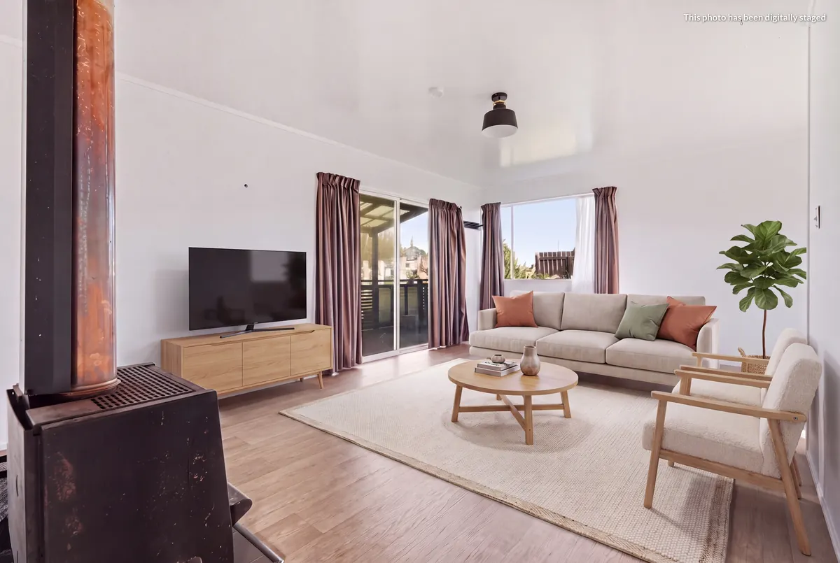 Staged lounge at 76 Takahe Road from beside the wood burner, with the digitally staged label top right