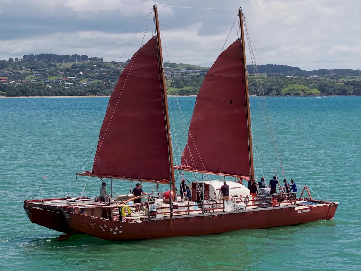 Waka under red sail in Mangōnui Harbour
